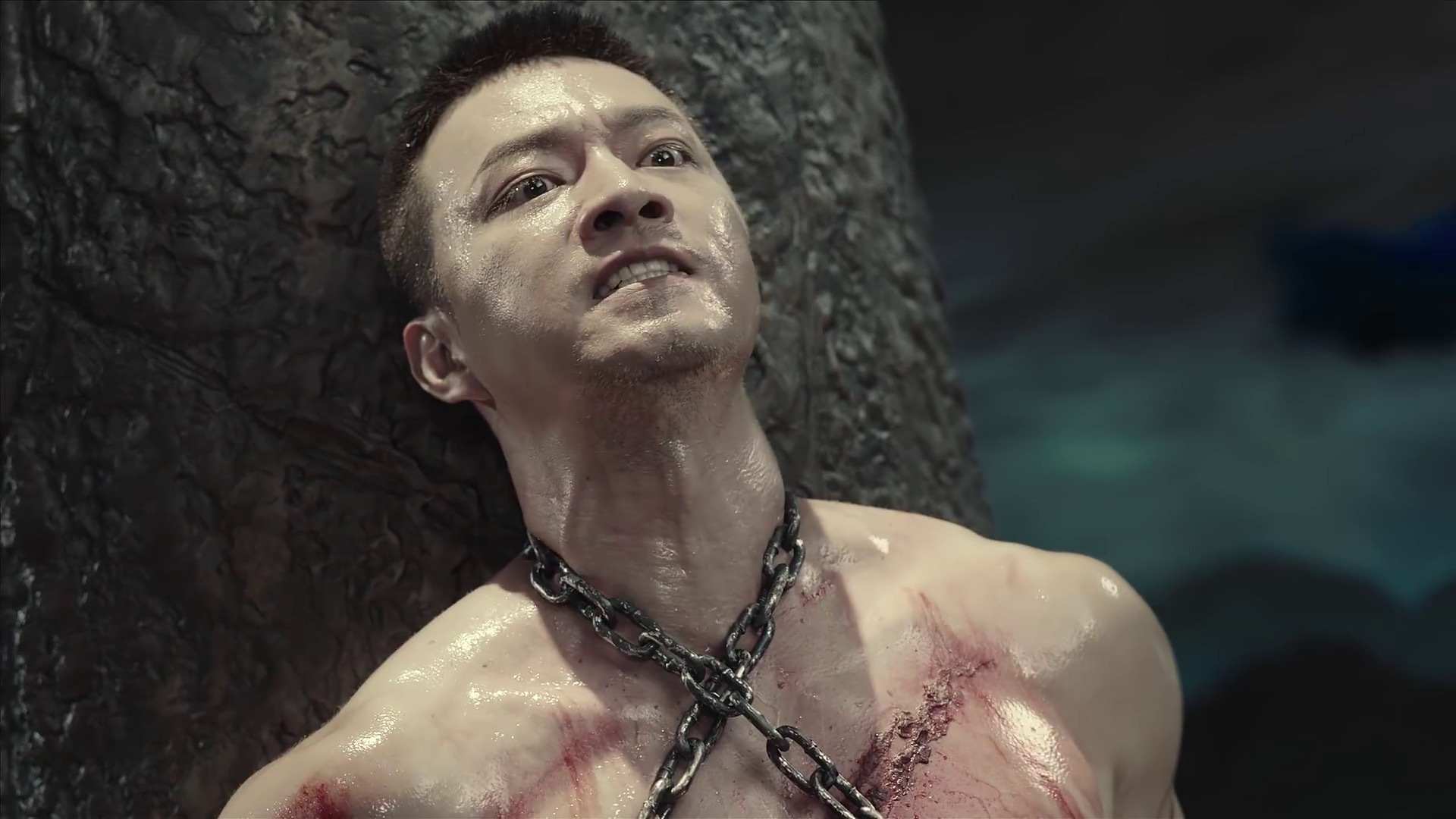 Chu Shuzhi is chained around the neck and chest against a column, being whipped